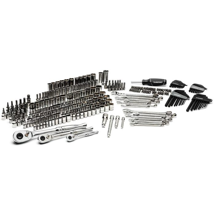 A collection of various metal tools, organized neatly, includes sockets, ratchets, and screwdrivers, arranged on a light surface for easy identification and access.