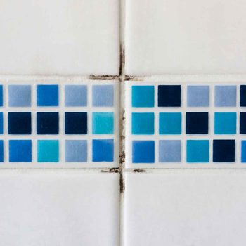 Colorful tiles display various shades of blue and white, placed in a grid pattern with visible grout lines, set against a plain white background.