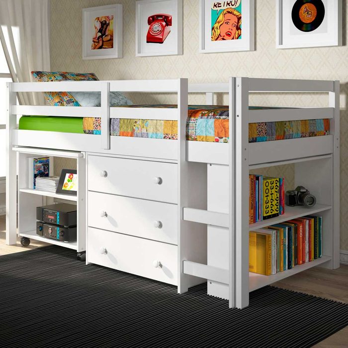 A white loft bed with colorful bedding sits above storage drawers and a bookshelf, surrounded by patterned wallpaper and framed artwork, on a black rug.