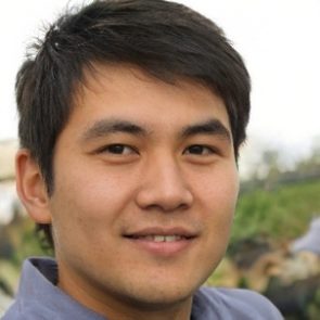 A young man smiles confidently, with short dark hair, set against a blurred, green outdoor background.