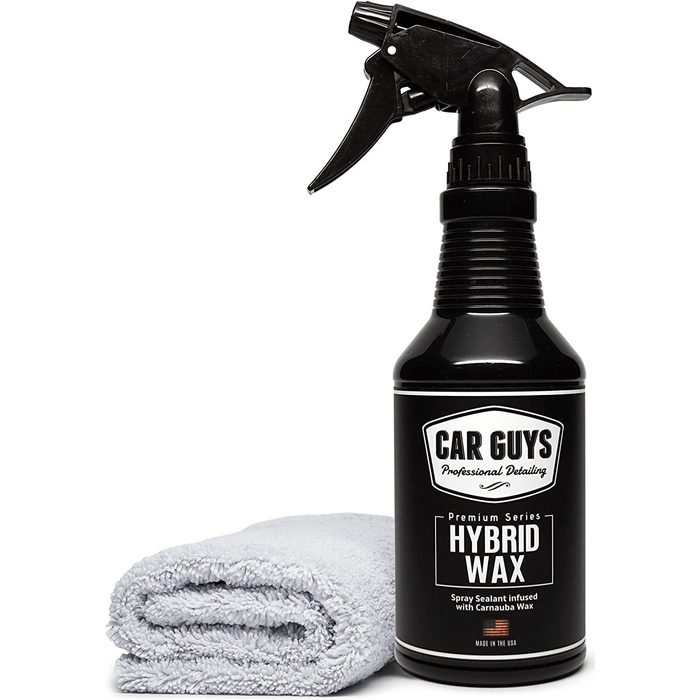 A spray bottle of hybrid wax stands beside a folded gray microfiber cloth, prepared for car detailing and maintenance in a clean indoor setting.