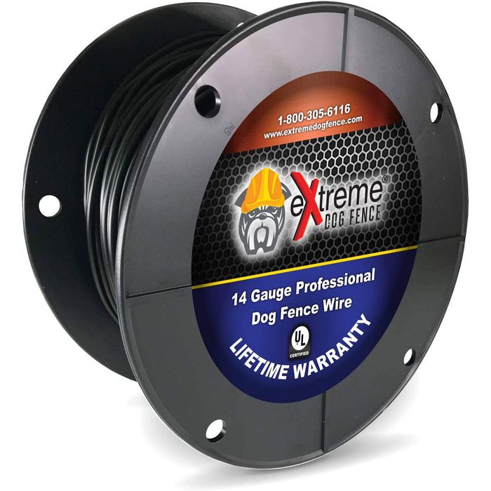 A spool of black 14-gauge dog fence wire sits upright, displaying a colorful label stating 