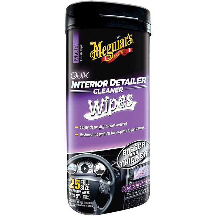 A container of interior cleaner wipes is displayed, labeled for safely cleaning surfaces, with graphics related to automotive detailing and a car dashboard in the background.