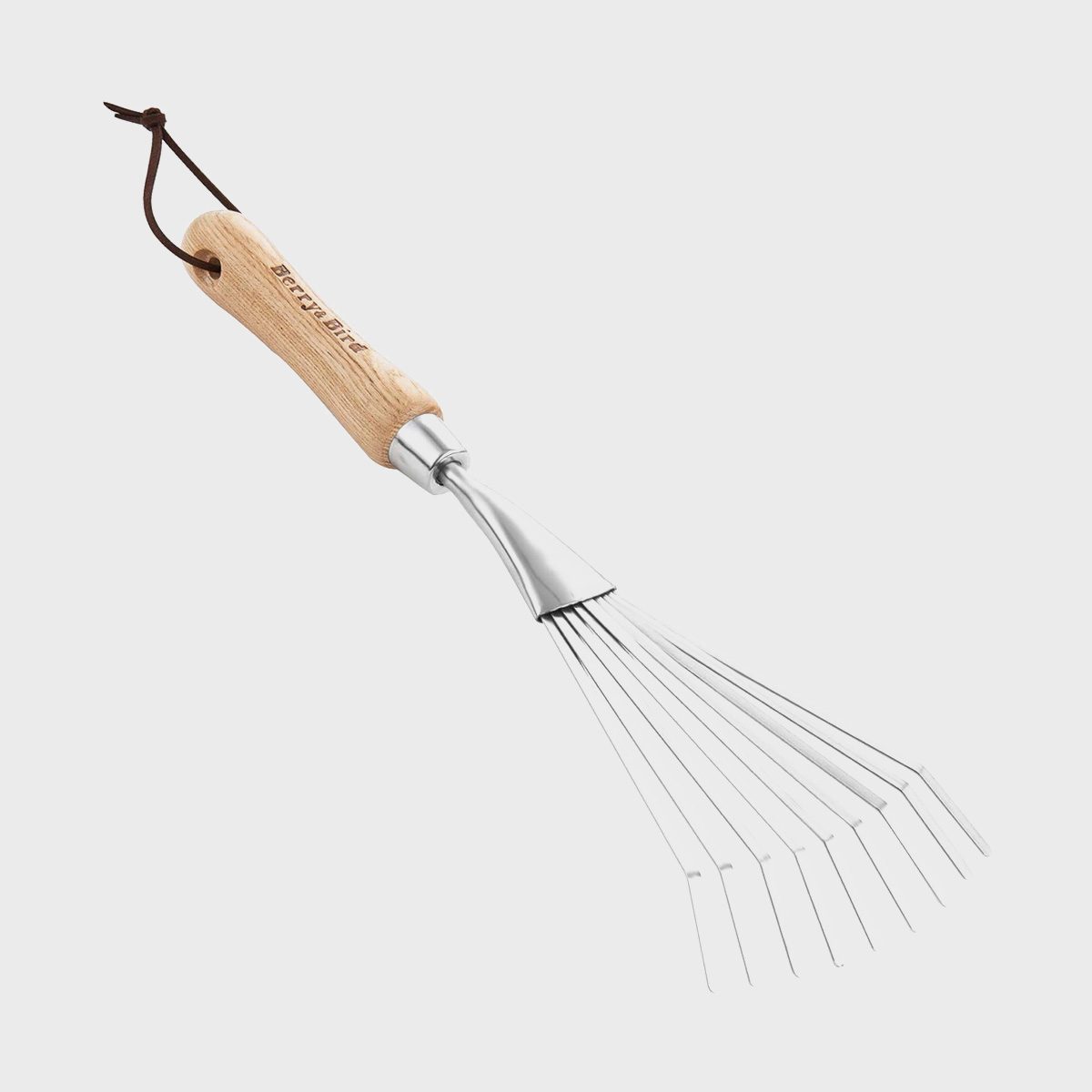 A metal hand rake with a wooden handle is positioned diagonally, designed for gathering leaves or debris in a garden or outdoor setting.