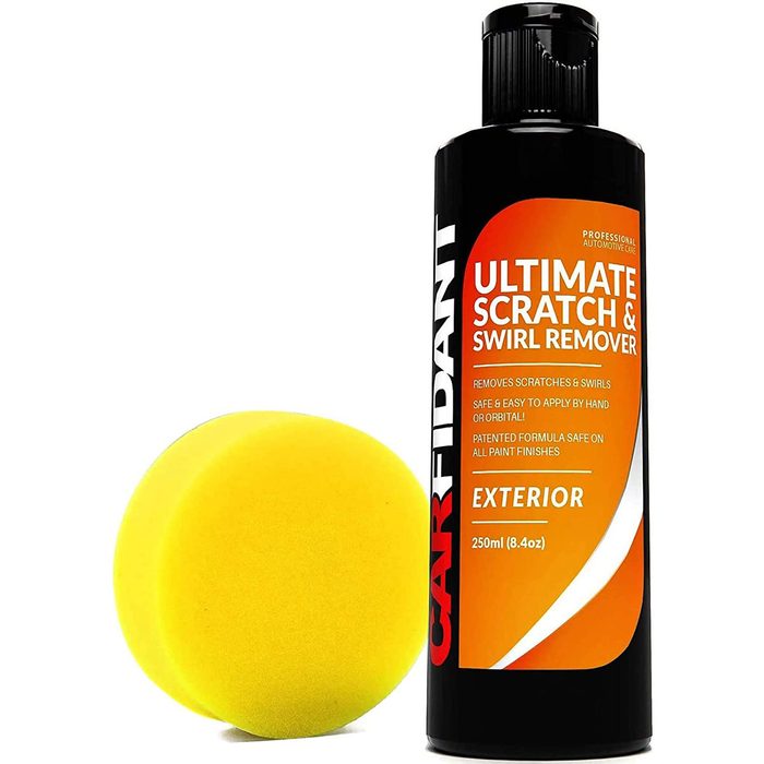 A bottle of scratch remover stands next to a yellow sponge, promoting surface cleaning for automotive finishes with a patented formula.