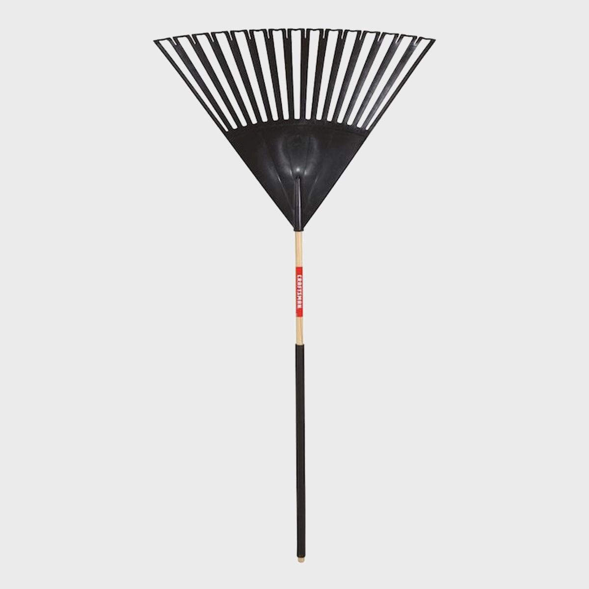 A black garden rake stands upright. Its wide, fan-shaped head is designed for gathering leaves. The handle is wooden, featuring a red label.