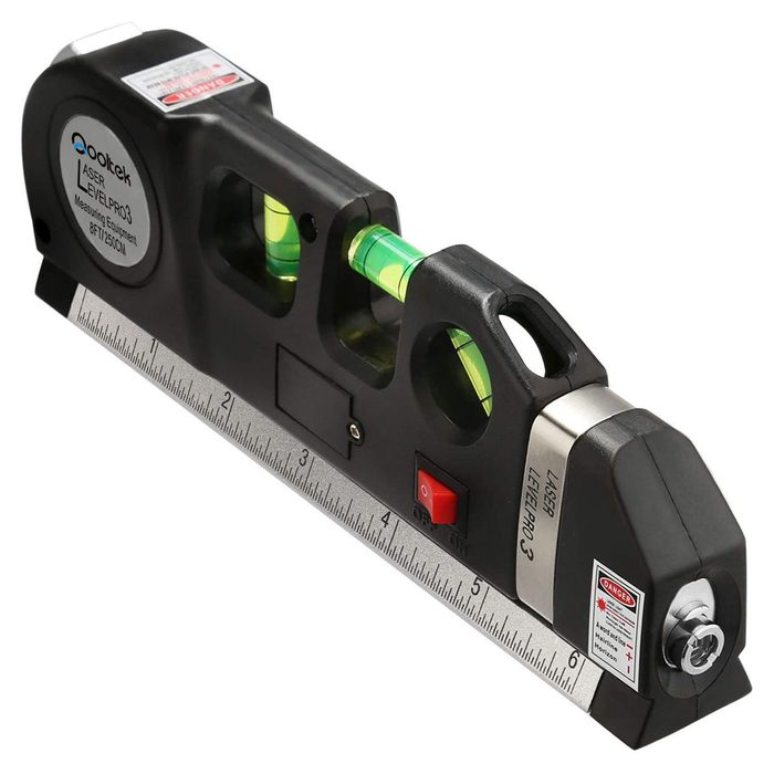 A laser level tool lies flat, showing a ruler and bubble levels. It is designed for precise measurements on construction or renovation projects.
