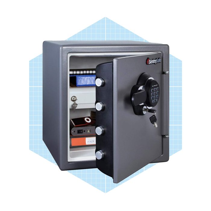 A gray safe stands open, displaying shelves with stacked items. It