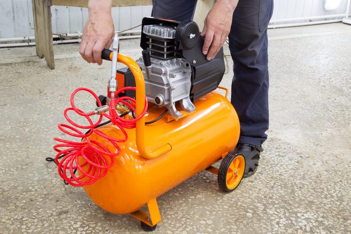 hands using an orange air compressor
