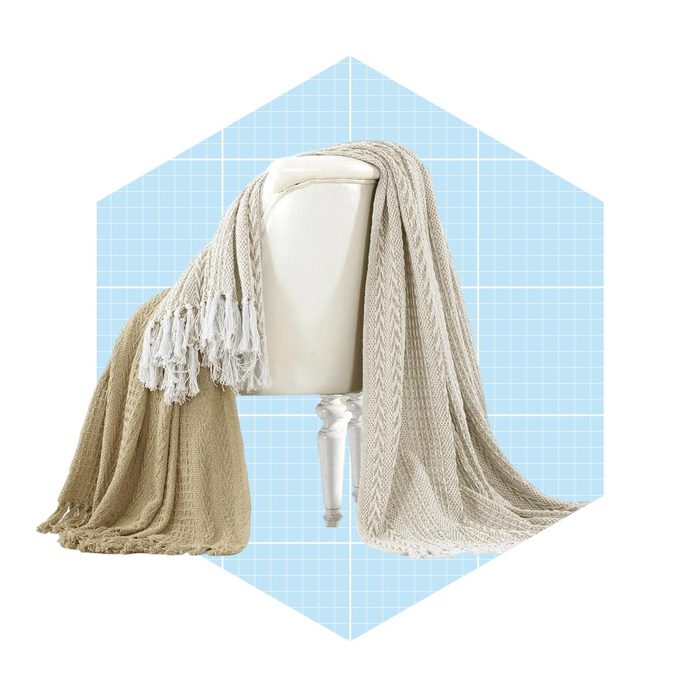 A decorative blanket drapes over a white pedestal, showcasing its textured fabric against a soft blue grid background.