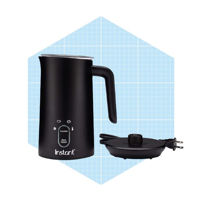 A black electric milk frother stands upright, featuring buttons for operation, next to a detachable base with a power cord, set against a light blue grid background.