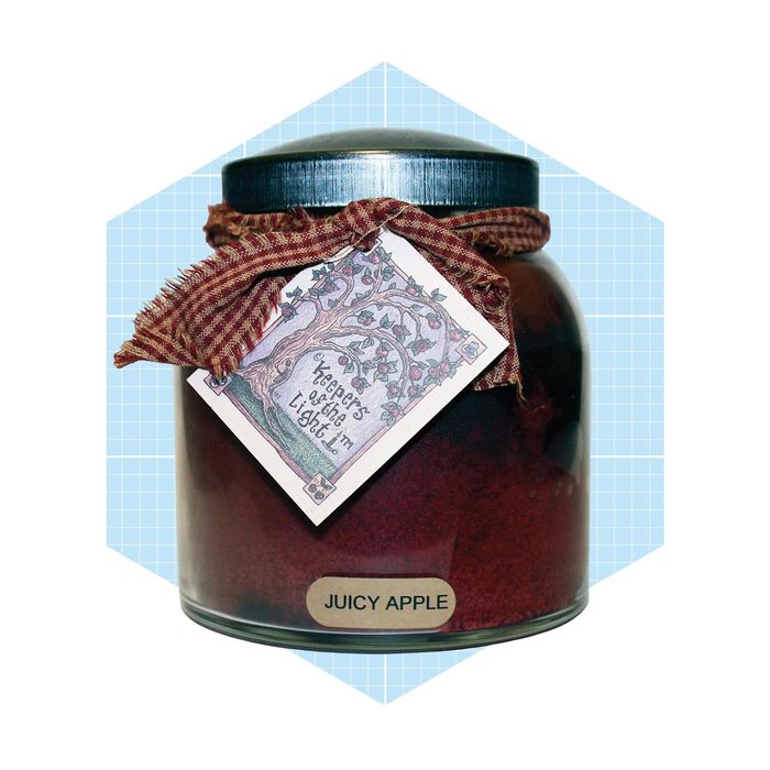 A glass jar filled with a reddish-brown substance is tied with a checked fabric ribbon, featuring a decorative label reading 