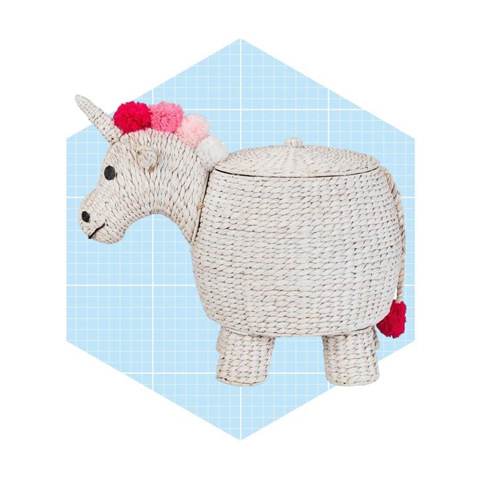 A woven storage container shaped like a unicorn, featuring a colorful mane and standing on four short legs, set against a light blue grid background.