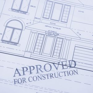Blueprints featuring detailed drawings of a house outline, marked “APPROVED FOR CONSTRUCTION,” indicating approval for building within a specified design framework.
