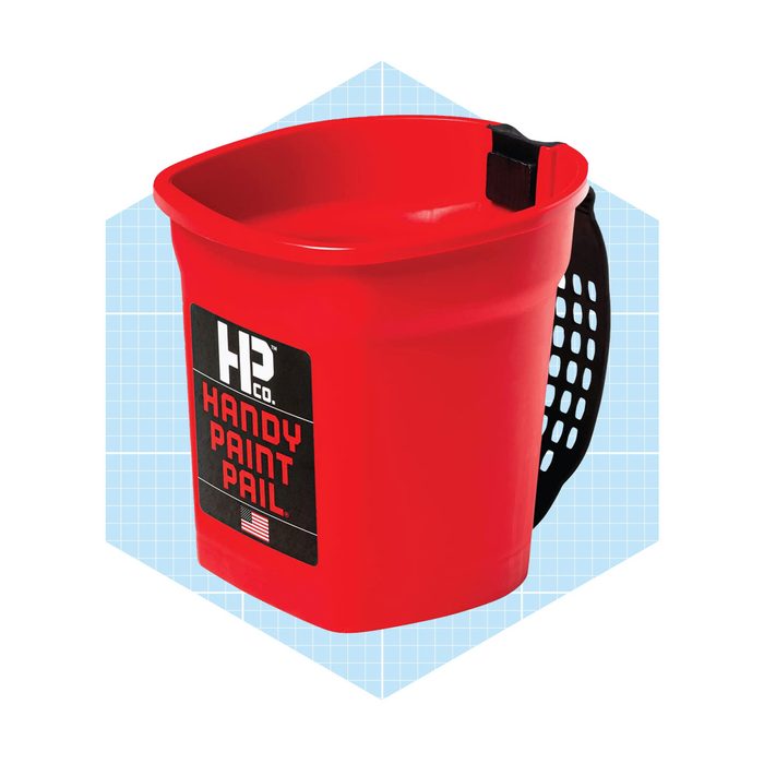 A red paint pail sits upright, designed for carrying paint. It features a sturdy handle and a label identifying it as a 