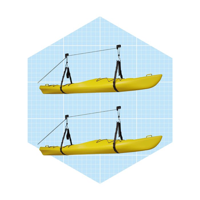 A yellow kayak is suspended by straps and pulleys against a light blue grid background, showcasing its profile from both sides.