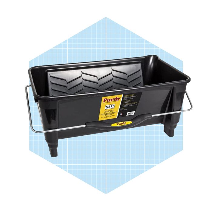 A black paint tray features a textured bottom for paint distribution, equipped with a handle for easy carrying, set against a light blue grid background.
