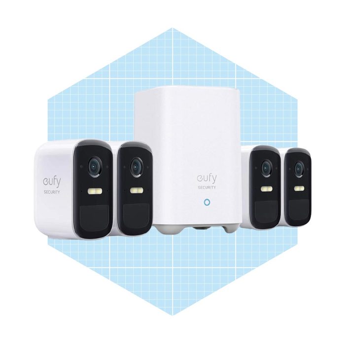 A set of four security cameras and a white hub are arranged together. They are designed for surveillance, set against a light blue grid background.