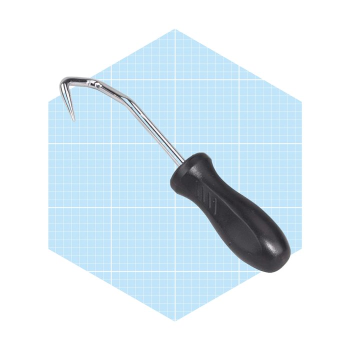 A metal dental tool with a curved hook is positioned prominently, featuring a textured black handle, set against a light blue grid background.