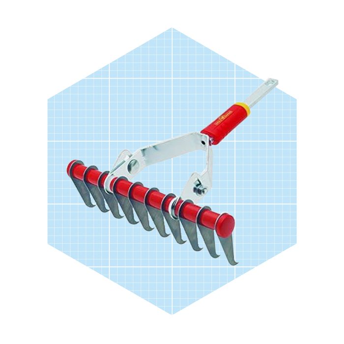 A metal rake with a red handle is positioned upright against a light blue grid background, ready for use in garden maintenance.