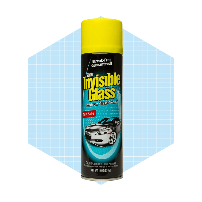 A spray can of Stoner Invisible Glass cleaner stands upright, advertising its streak-free formula amidst a light blue hexagonal background.