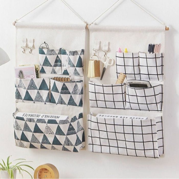 Hanging fabric organizers feature triangular and grid patterns, holding various items like scissors and notebooks against a white wall, enhancing storage and decor.