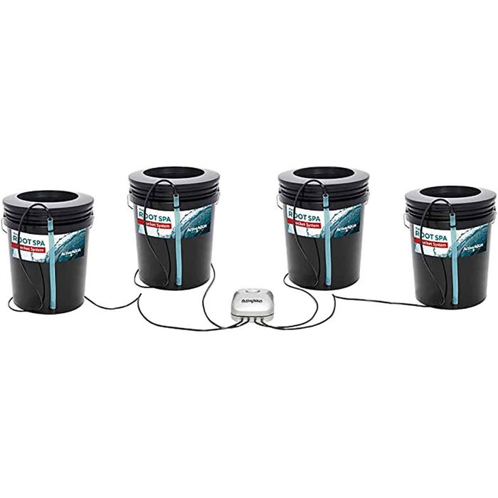 Four black buckets are connected by hoses to a central unit, designed for a hydroponic spa system. The setup is organized and functional.
