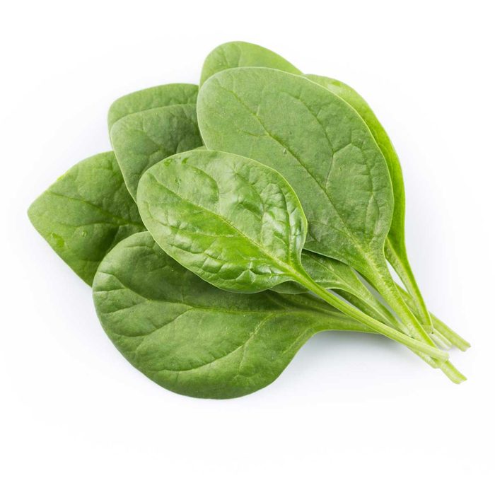 A pile of fresh spinach leaves rests against a clean, white background, showcasing their vibrant green color and smooth, slightly wrinkled texture.