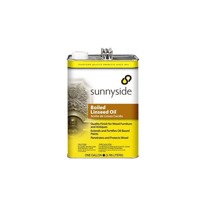 A metal can of boiled linseed oil sits upright, labeled prominently with product details. It is designed for wood finishing and paint fortification.