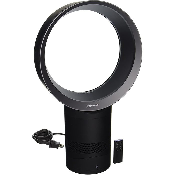 A circular bladeless fan sits on a black base, blowing air smoothly. It includes a power cord and a small remote control.