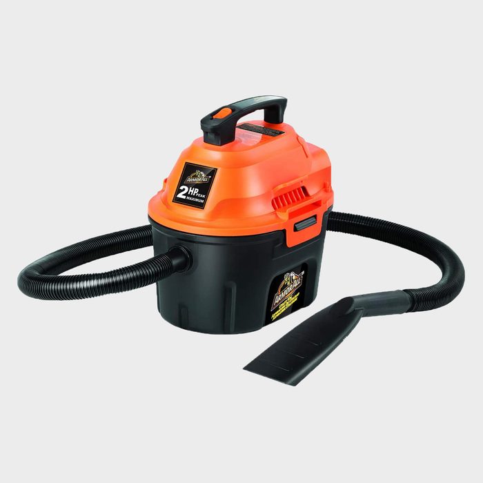 A compact vacuum cleaner with an orange top, black body, and flexible hose, designed for cleaning tasks in various environments.