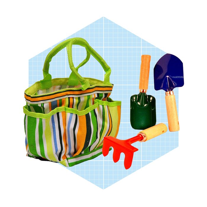 A striped garden bag sits alongside colorful mini gardening tools: a red rake, green scoop, and blue shovel, set against a light grid background.