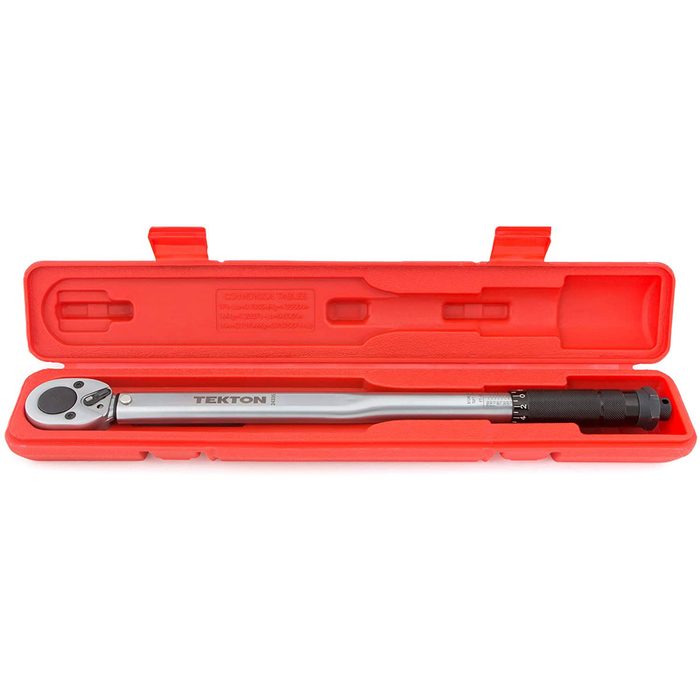 A torque wrench rests within a bright red plastic case, designed for precise tightening of bolts, with measurement markings visible along its handle.
