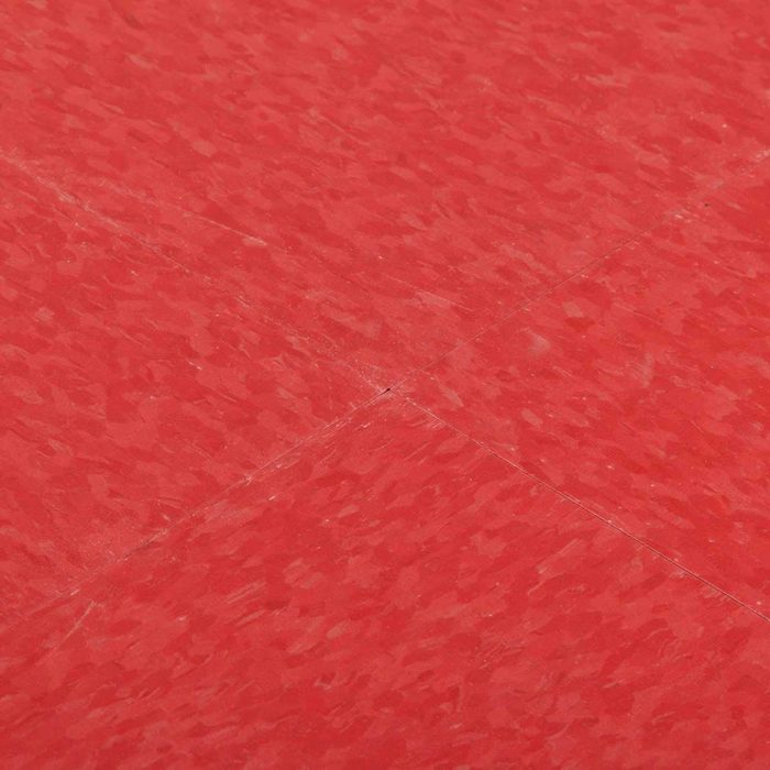 A red floor surface has visible texture, with intersecting lines creating a grid pattern, suggesting a well-maintained indoor or outdoor area.