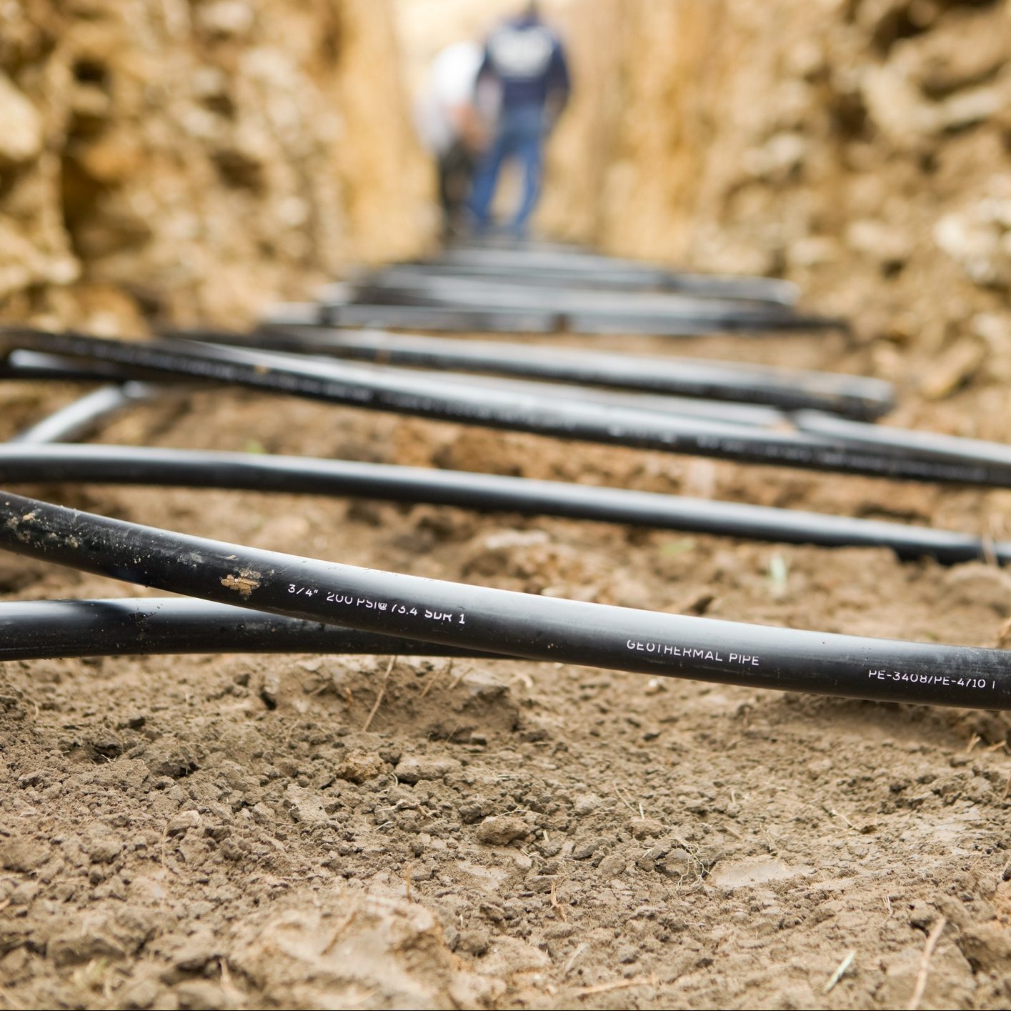 Workers Laying Geothermal Coils In An Underground Trench