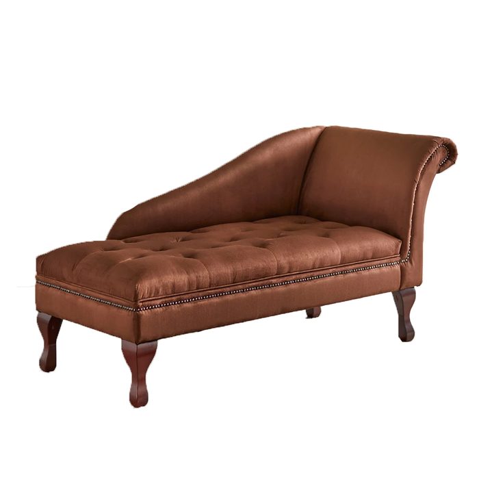 A tufted brown chaise lounge rests on four wooden legs, featuring a curved back and decorative nailhead trim, suitable for relaxed seating in any room.