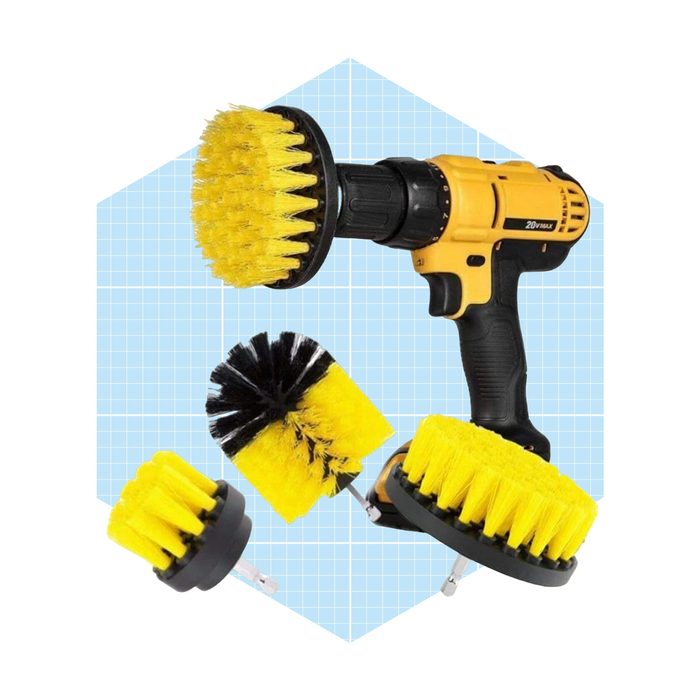 A yellow power drill holds a yellow scrub brush attachment, surrounded by additional brushes, set against a light blue grid background.