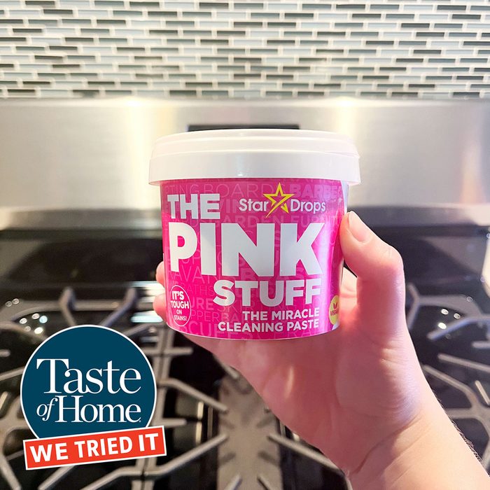 A person holds a pink cleaning paste container labeled 