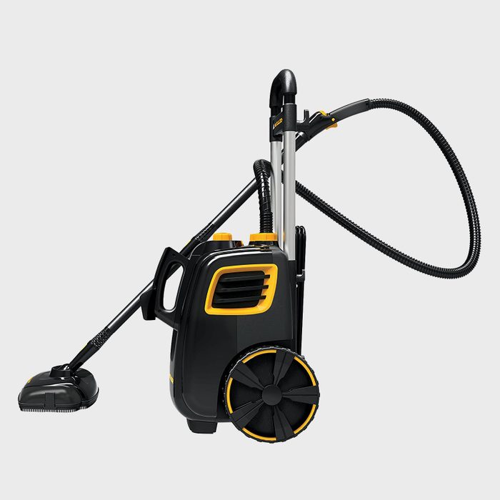 A black and yellow vacuum cleaner, upright with a hose attached, stands ready for use on a gray background, featuring wheels for mobility.