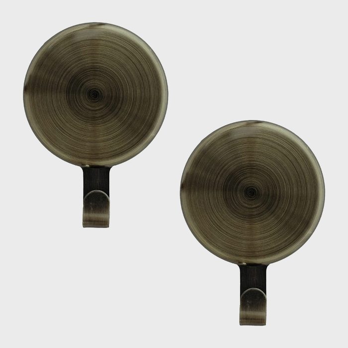 Two round, metallic objects with spiral patterns sit side by side, each featuring a small hook at the base for hanging.