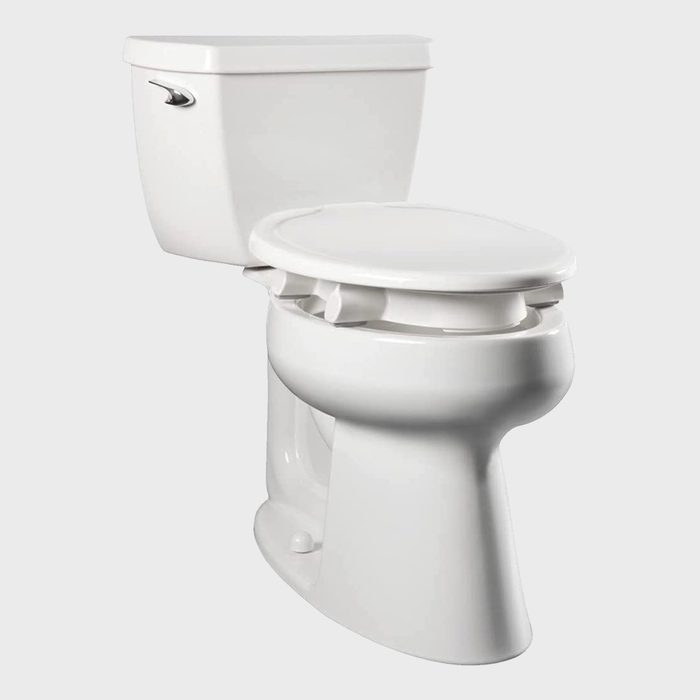 A white toilet with a tank and seat is positioned, ready for use in a neutral gray background.