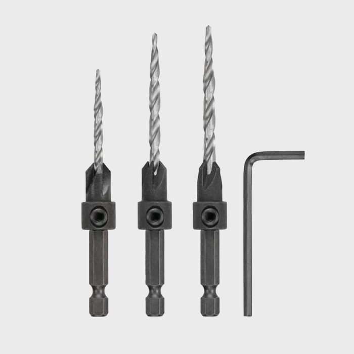 Three drill bits and an Allen wrench are arranged horizontally, with varying lengths and twists, against a light gray background, ready for use.