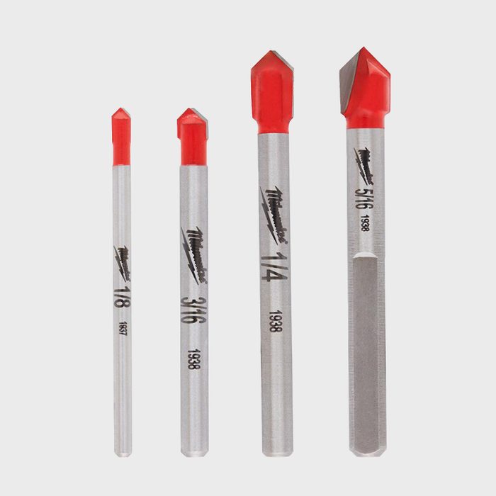 A set of four metal drill bits stands vertically, each with a red tip, labeled with various sizes and numbers, on a plain white background.