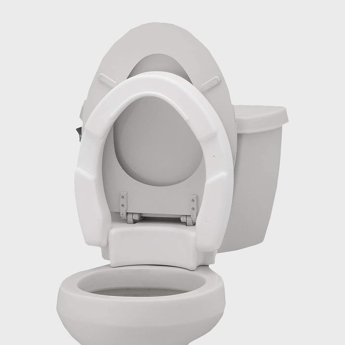 A white toilet is open, featuring a removable seat. It’s placed in a neutral environment, suggesting cleanliness and functionality for personal hygiene.