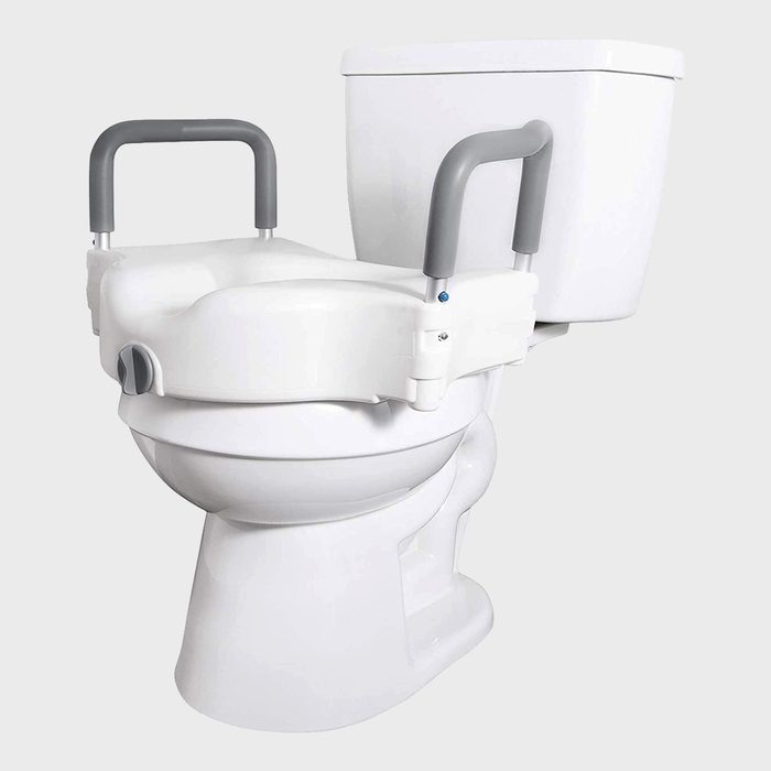 A toilet features a raised seat with gray armrests for support, designed to aid individuals in sitting and standing comfortably.