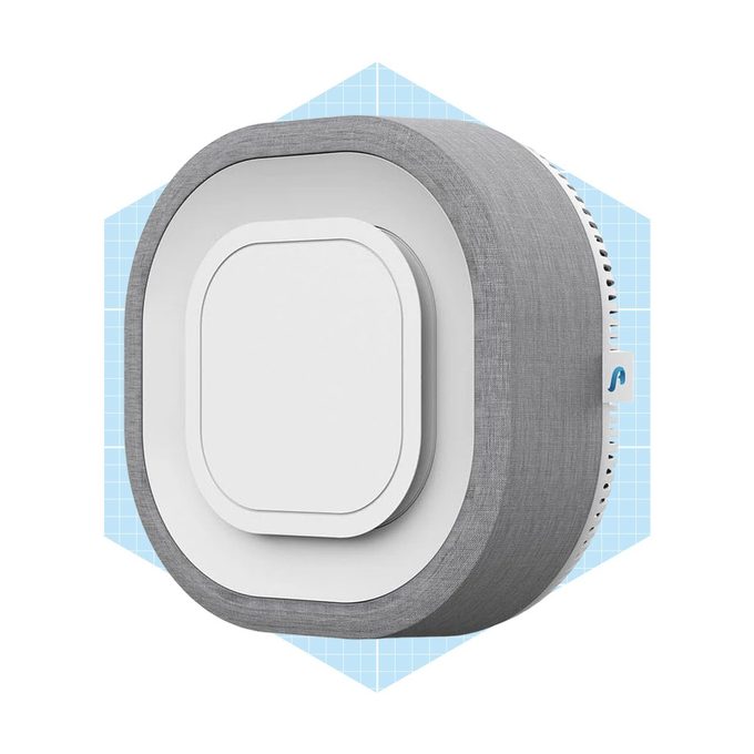 A round, gray-wrapped device with a white center sits against a light blue grid background, designed for smart home connectivity.