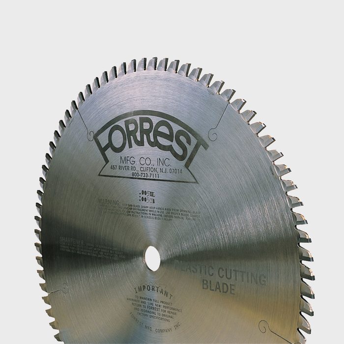 A circular saw blade with sharp teeth spins, designed specifically for cutting plastic. It features engravings indicating brand and safety warnings.