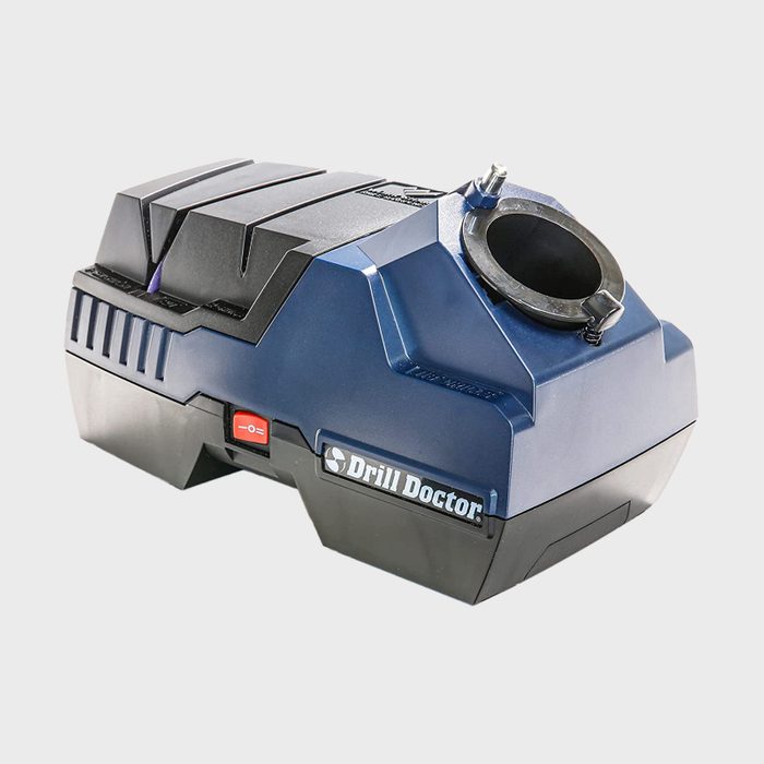 A blue electric drill sharpener stands on a surface, featuring a circular opening for drill bits and a power switch below it, ready for use.