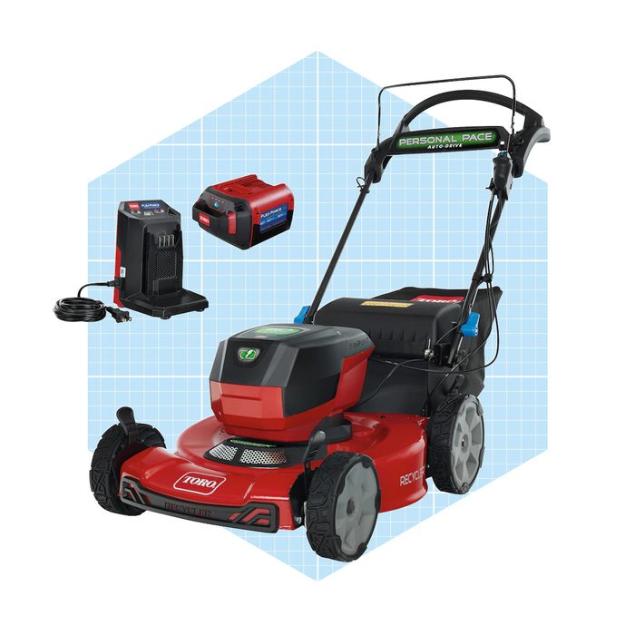 A red and black electric lawn mower stands on a light blue grid background, accompanied by two batteries and a charger, ready for use.