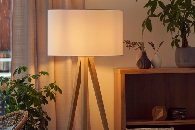 View of tripod lamp in a cozy living room spending warm light